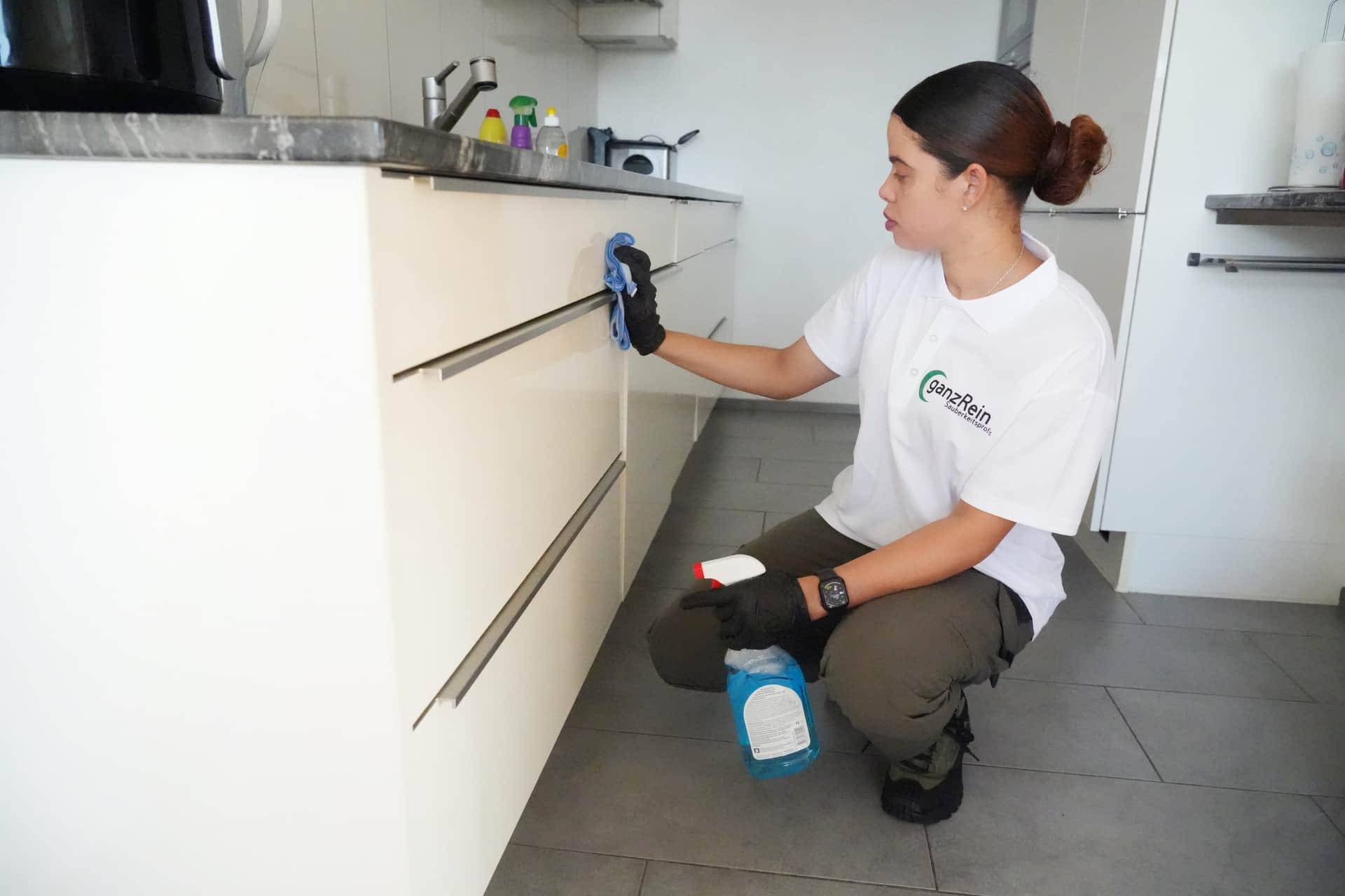 Reinigungskraft reinigt gründlich die Dunstabzugshaube in einer Küche in Bern