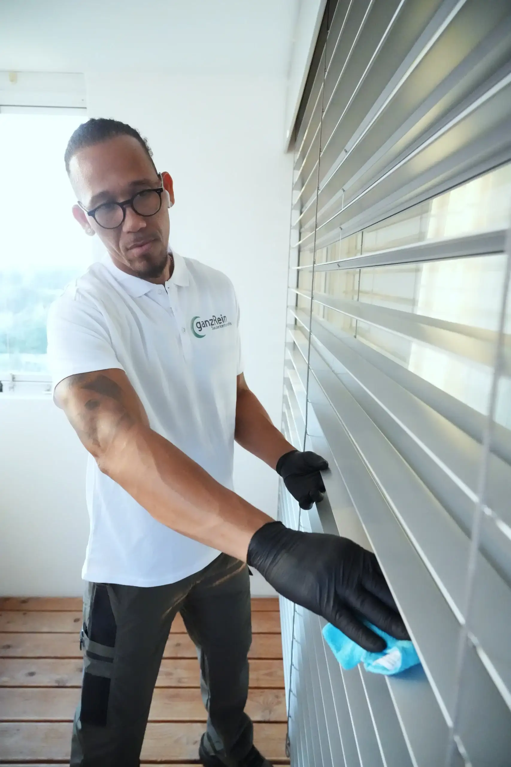Reinigungskraft putzt große Glasfenster mit professionellem Equipment