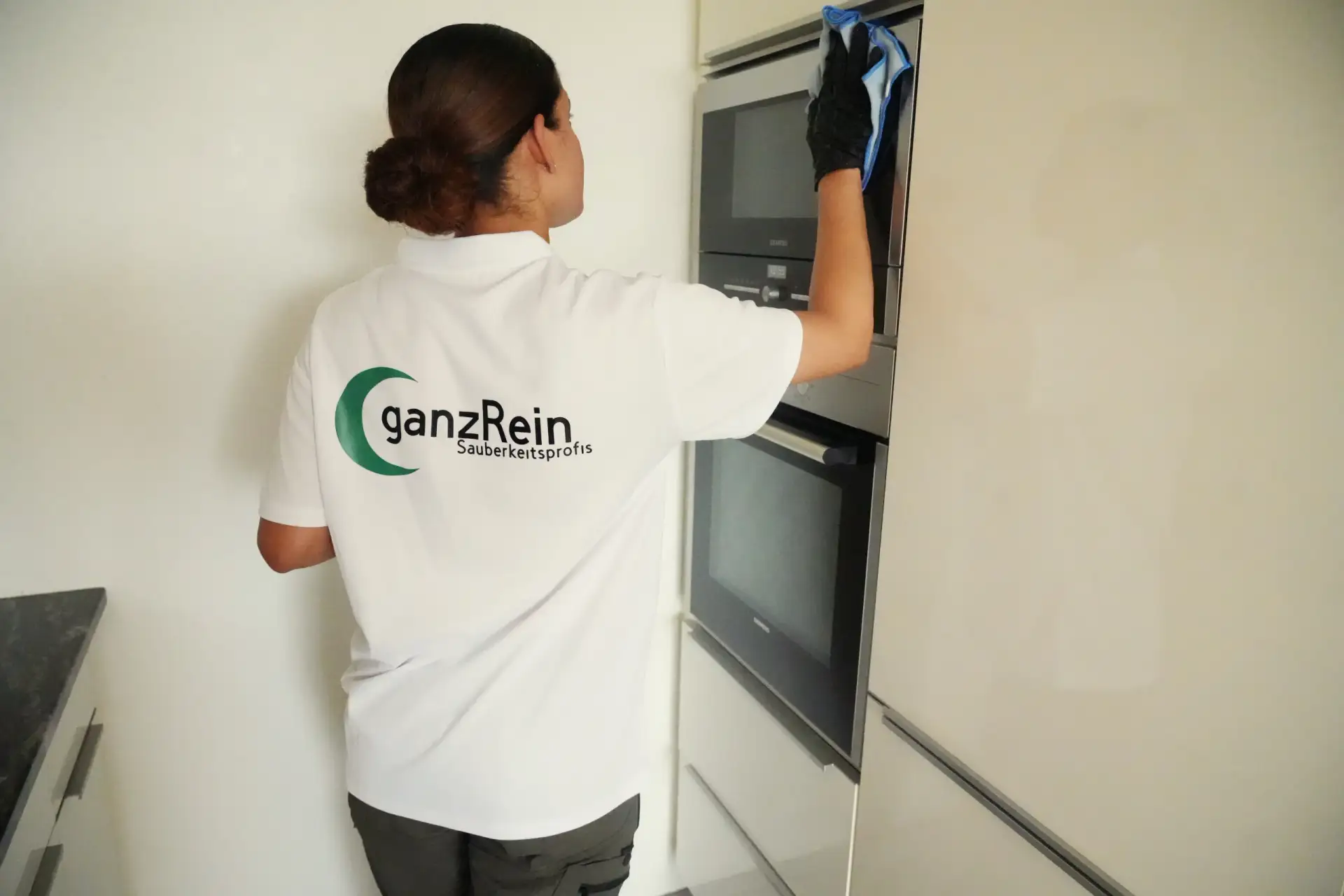 Reinigungskraft säubert gründlich eine moderne Küche in einer Wohnung in Bern