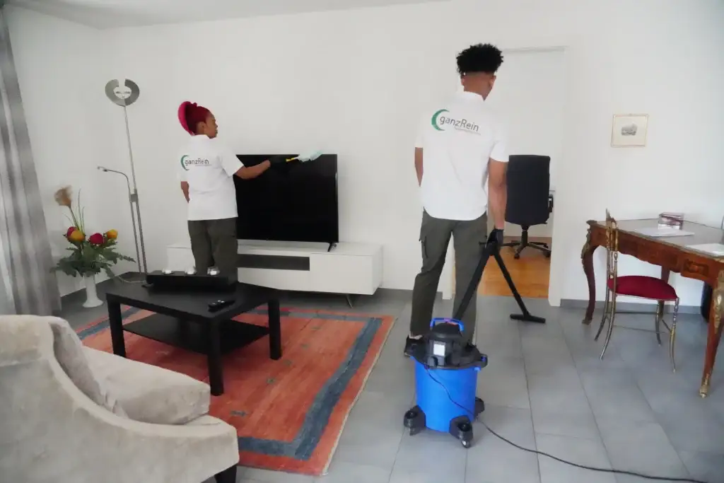 Putzfrau reinigt das Wohnzimmer eines Hauses mit einem Staubsauger